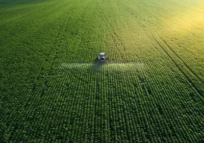 a tractor moves through a green field